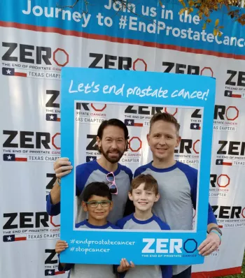 Chris Hartly and husband and two sons at a ZERO run/walk event holding up a selfie frame