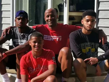 A black man and his three sons sitting on the steps outside of a house