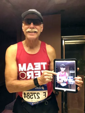 Carl taking a selfie  of a selfie in the mirror prepping for the Boston marathon wearing Team ZERO gear
