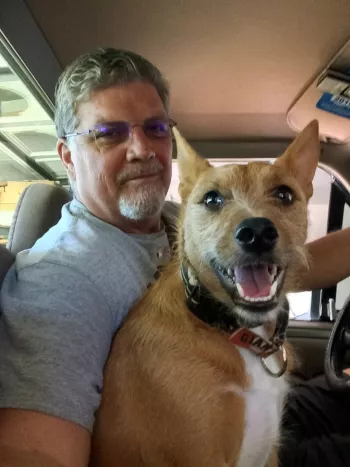 Jon Albrecht and his scrappy looking dog riding in the drivers seat of a truck