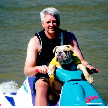 Rodney O. Hardcastle and a bulldog wearing a shirt riding a jetski