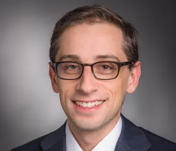 Young man with rectangle glasses posing for a headshot