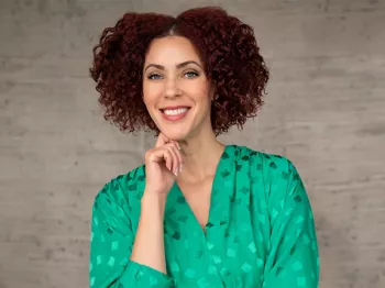 A Black woman in a green top smiling at the camera