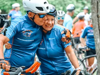 A couple, Scott and Katy Freitag, embracing while standing over their bicycles