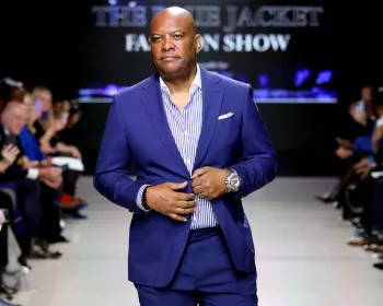 A Black man wearing a blue suit on the runway of the Blue Jacket Fashion Show