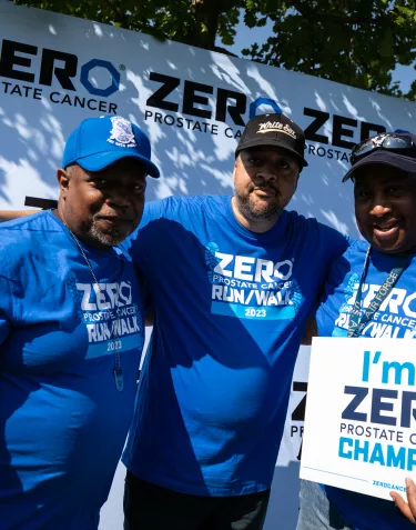 Three African American men wearing blue t-shirts and carrying a We're Champions sign