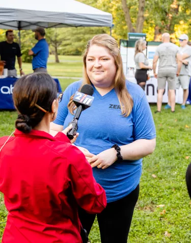 A journalist interviewing a blond woman in a blue t-shirt