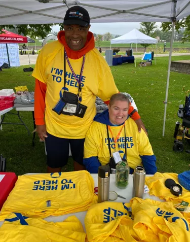 Two people wearing yellow shirts with the sign Volunteer
