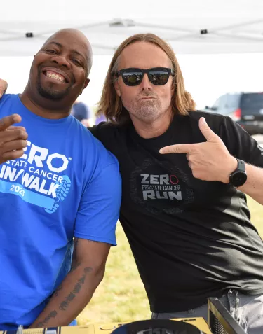 An African American man in a blue tshirt and a Caucasian man with long hair and black t-shirt 
