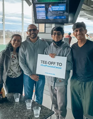 Indian family with two boys holding a ZERO Tee-off sign