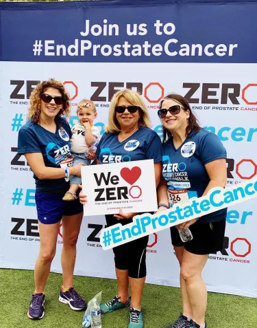 Group of three women and an infant in front of a ZERO banner