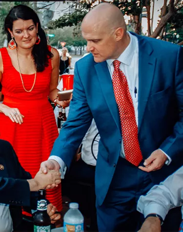 Jamie Bearse shaking hands with a man sitting down at the 2016 Congressional BBQ