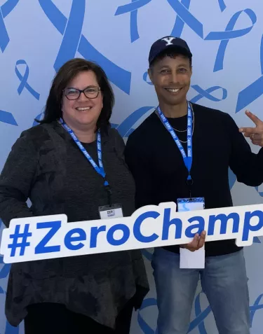 A woman and a man holding a #ZEROChampion sign