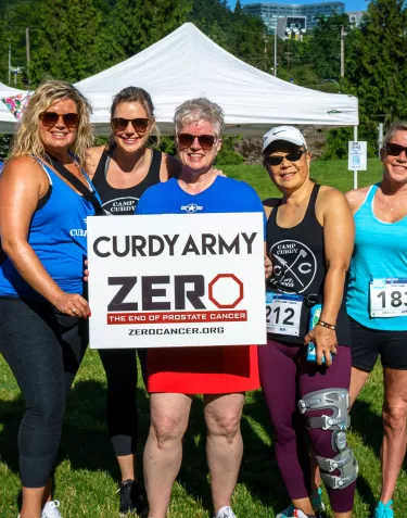 Group of women at a sports event holding a Curdy Amy sign