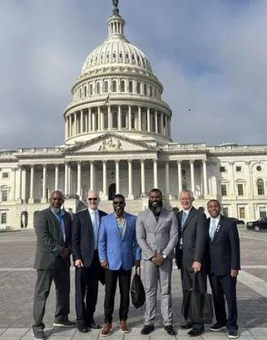 A group of men dressed in suits in front of the Capitol