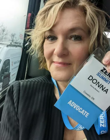 Woman with short blond hair holding a tag Advocate