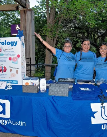 Three people wearing blue t-shirts in front of a booth