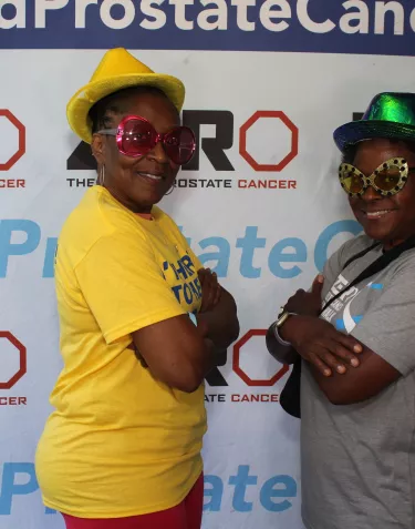 Two African American women wearing funky glasses and standing in front of a ZERo banner