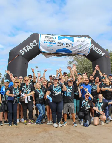 A large group of people holding their hands up under the inflatable arch at the Napa Valley Run/Walk in 2023
