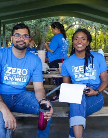 A man and woman smiling while sitting at a picnic table at the 2023 Run/Walk in Tampa