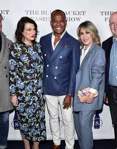 A group of two men and two women surrounding fashion designer, Fredrick Anderson, in front of a step and repeat at the Blue Jacket Fashion Show