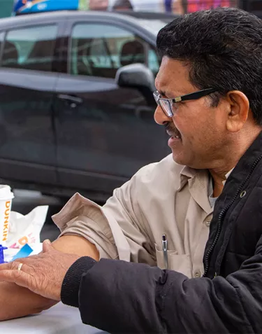 Hispanic man with his sleeve rolled up at a mobile testing site