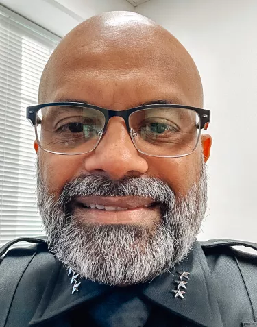 A Black police office with glasses and a grey beard