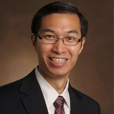 Man of Asian decent wearing a suit and a tie and glasses