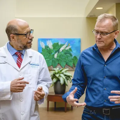 A doctor and a blond male patient in a blue shirt talking