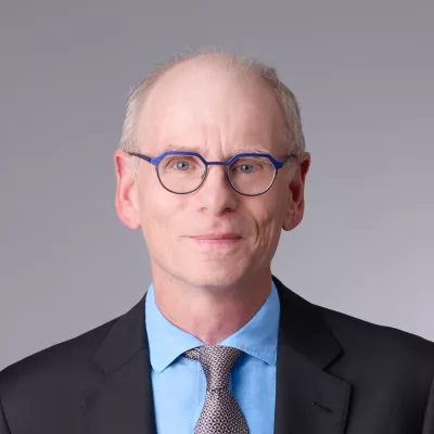 An older white man wearing a suit and tie with glasses