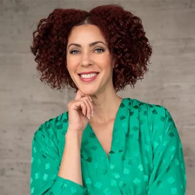 A Black woman in a green top smiling at the camera