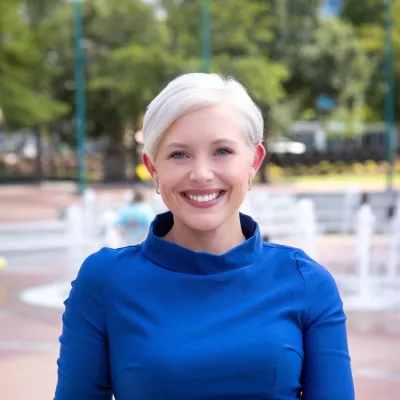 Courtney Bugler in a blue dress standing in front of water fountains