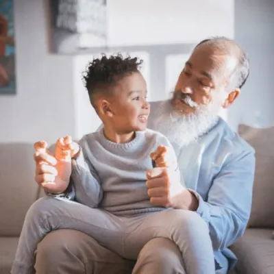 Man sitting on couch with small child on lap smiling at each other