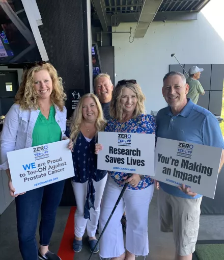 Group of people holding tee off signs