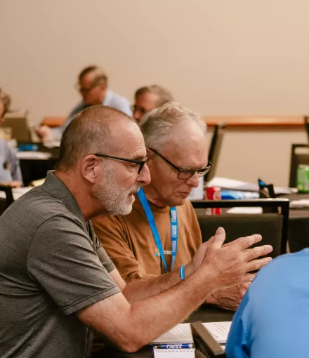 Two men sitting together and talking at the SGL training in 2024.
