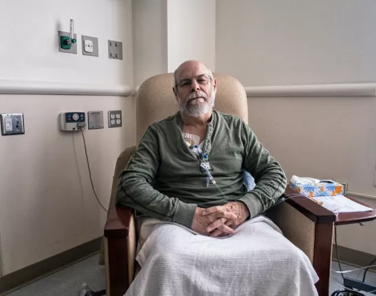 A man sitting in a chair in the hospital receiving chemotherapy treatment