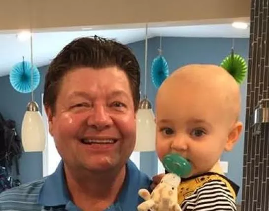 Jim Obert holding a child with a pacifier in its mouth