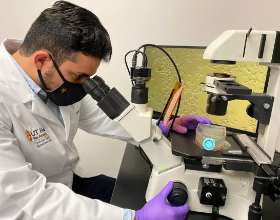 Jose Gutierrez looking in a microscope in the lab