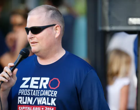 Paul Taylor wearing a ZERO shirt and speaking into the microphone at an event