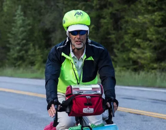 Man on his journey cross country with bicycle packed full of bags, a yoga mat, safety gear and more