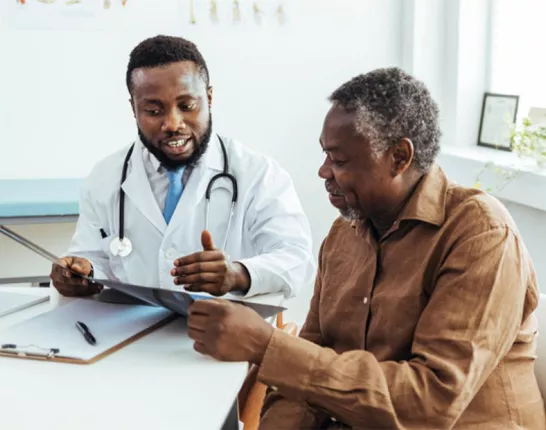 A Black man talking to his doctor at a desk