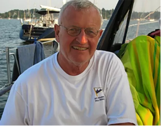 Old man smiling on a boat out on the water surrounded by land