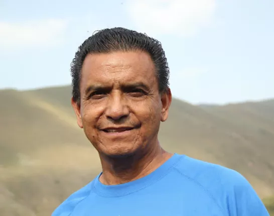 Latin man in blue shirt standing in front of barren mountains