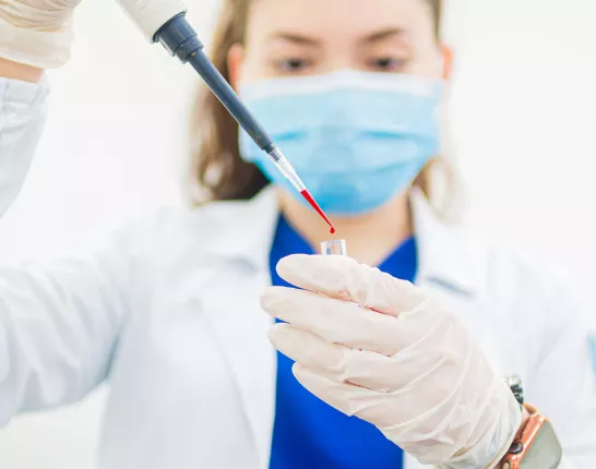Woman in a Lab Coat Holding a Test Tube