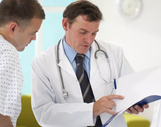 A doctor and a male patient in a gown talking