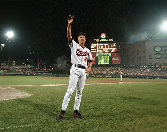 Cal Ripken Jr. standing on a baseball field holding his arm up