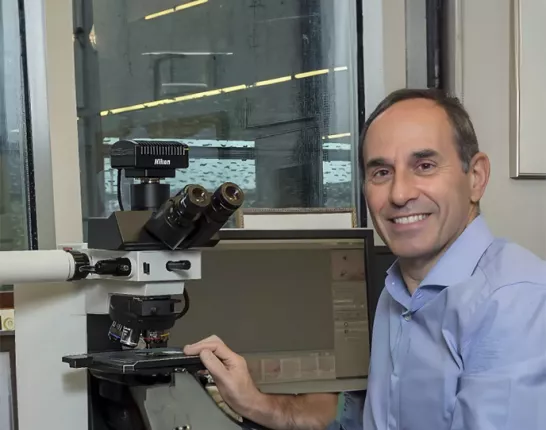 Dr Jonathon Epstein posing next to a Nikon slide viewing microscope