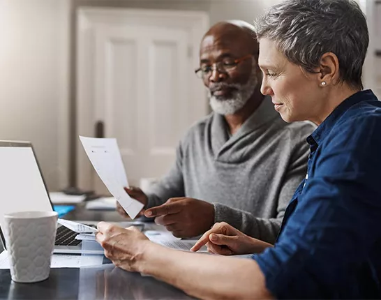 A man and woman sitting at a desk looking at paperwork 