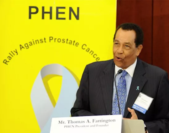 Thomas A. Farrington speaking at a podium with a PHEN sign behind him