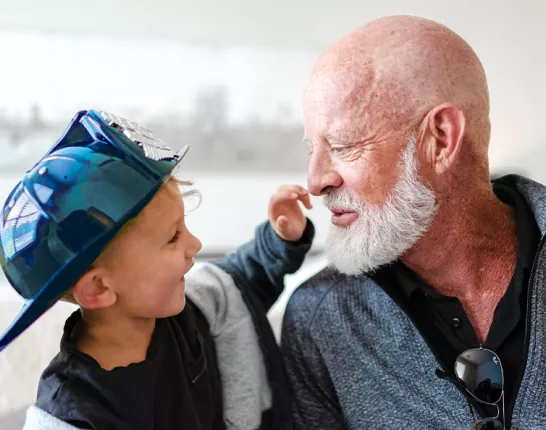 Prostate cancer survivor, Jeff, and his grandson who is wearing a blue firefighter hat